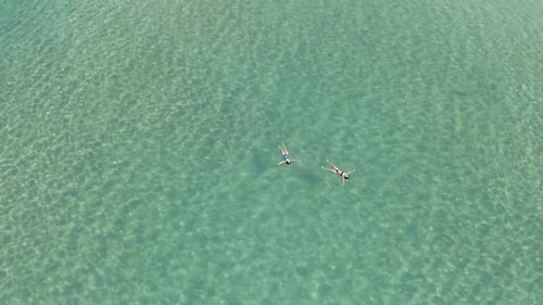 Women Floating in Clear Turquoise Ocean Water