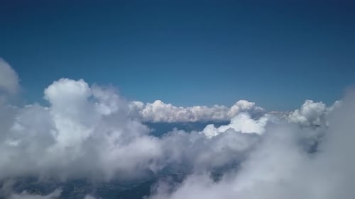 Luftflug durch Wolken über Berglandschaft