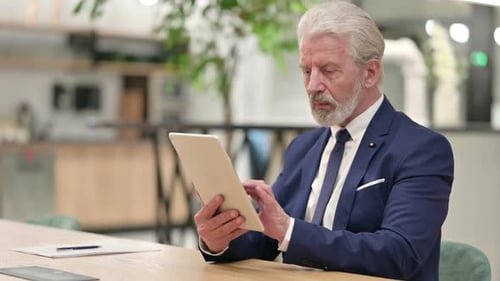 Senior Man Using Tablet in Modern Workplace