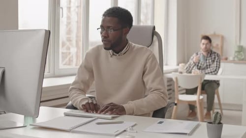 Afroamerikanischer Mann arbeitet im Büro am Computer