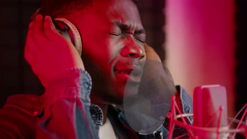 Emotional Black Guy Wearing Headphones Singing To Professional Microphone In Music Studio