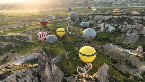 Hot air balloons fly over the mountainous landscape of Cappadocia, Turkey.