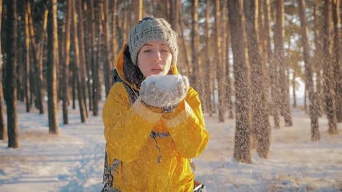 Beautiful Woman Blowing in the Snow in Pine Winter Forest