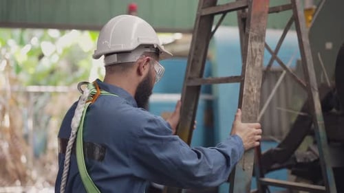 Adult Climbing Ladder in Industrial Workplace Wearing Gear