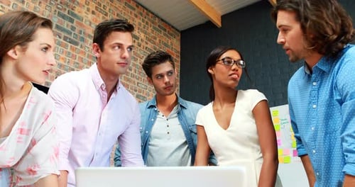 Diverse Team Collaborating Around Laptop in Modern Office