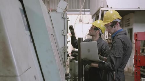 Team maintenance engineer using laptop computer control machine in factory together.