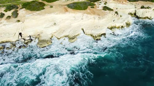 Flying Over Rocky Coastline Alongside Cliffside with Blue Mediterranean Sea Ocean Water Towards the