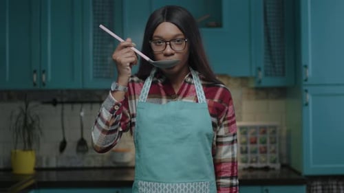 Woman in Apron Tasting Food With Spoon