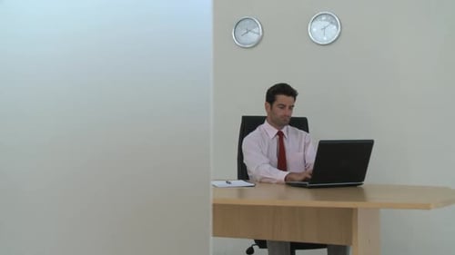 LS Tracking Left OF A BUSINESSMAN SAT AT A DESK WORKING ON A LAPTOP