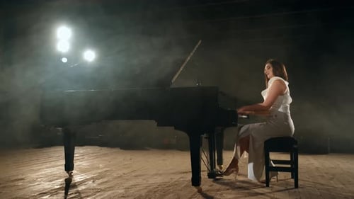 Woman in Dress Playing Grand Piano on Stage