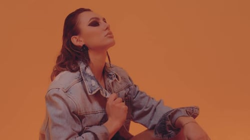 Woman in Denim Jacket Posing on Orange Background