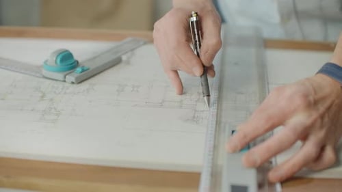 Close Up of Architect Hands Making House Blueprint in the Office Near Window