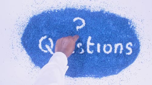 Hand Writes the Word Questions on Blue Fragments