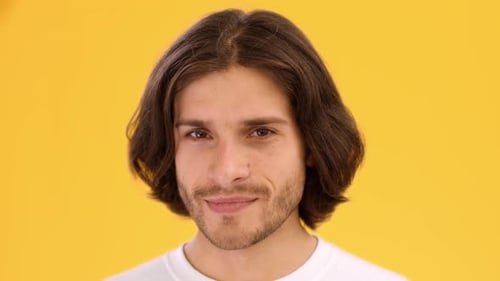Man Smirks and Winks on Yellow Background
