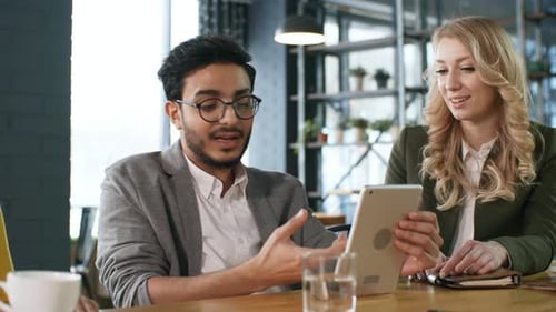 Arab Businessman Using Tablet and Speaking with Colleagues in Cafe
