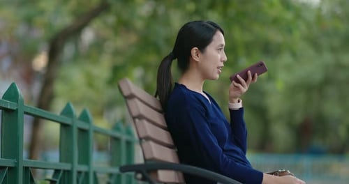 Woman Using Phone in Park on Park Bench