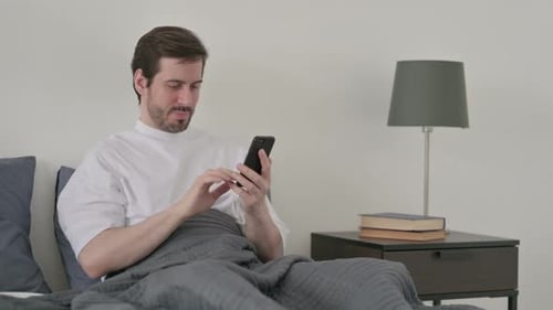 Man in Bed Upset by Phone Content