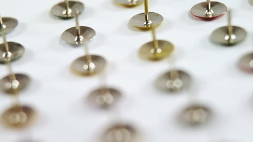 Close Up of Metal Push Pins on White Surface