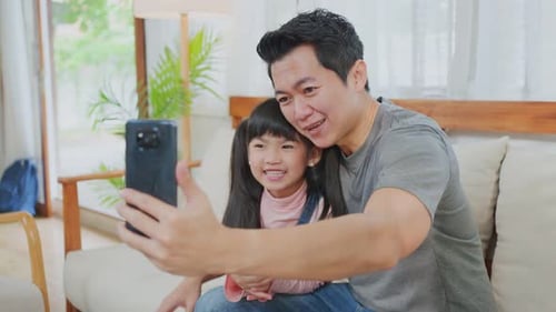 Loving Father and Daughter Taking Selfie on Couch