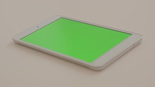 Silver tablet PC with green screen display on white reflective background 4K 2160p UltraHD footage -