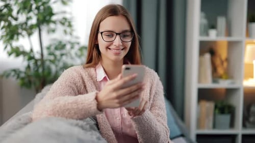 Young Woman Smiling while Using Smartphone at Home