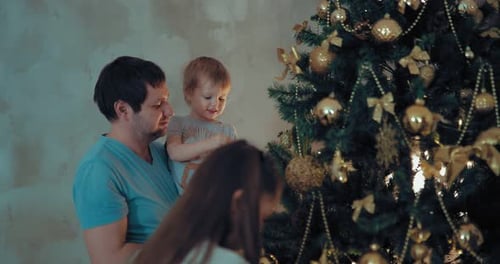 Family Decorates Christmas Tree with Golden Ornaments