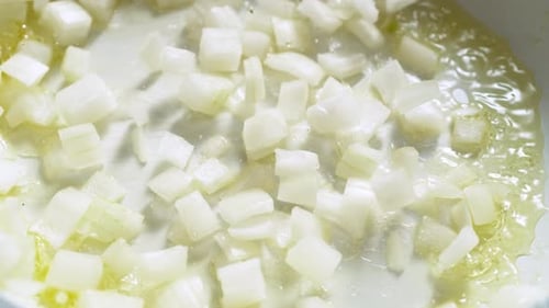 Diced Onions Sizzling in Oil on Pan