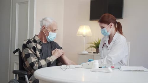 Der Arzt impft einen Rentner und zeigt den Daumen
