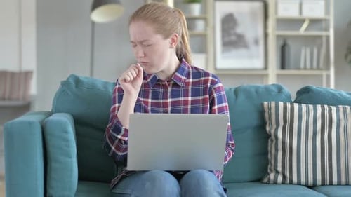 Young Woman Coughing While Using Laptop at Home