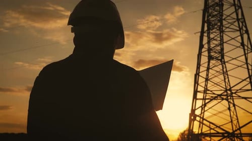 Silhouette of Engineer Standing on Field with Electricity Towers. Electrical Engineer with High