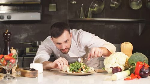 Chef Carefully Plates Fresh Green Salad in Kitchen