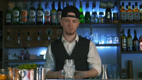 Young Adult Bar Tender Shakes Cocktail at Bar