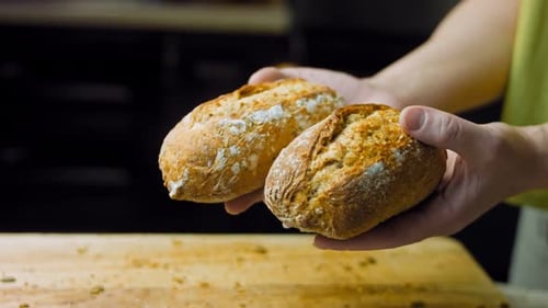 Hands Hold Fresh Baked Bread Rolls in Kitchen