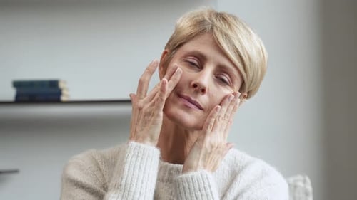 Woman Massaging Face in an Indoor Setting