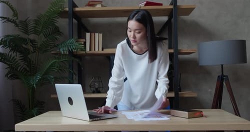 Woman Working at Desk with Laptop and Charts