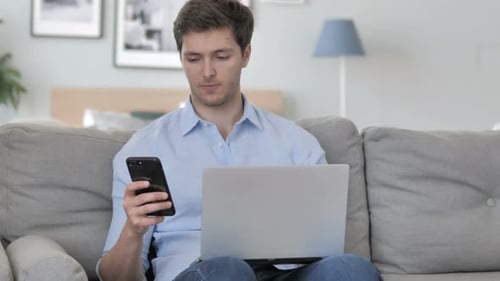 Man Using Smartphone for Work, Sitting on Couch