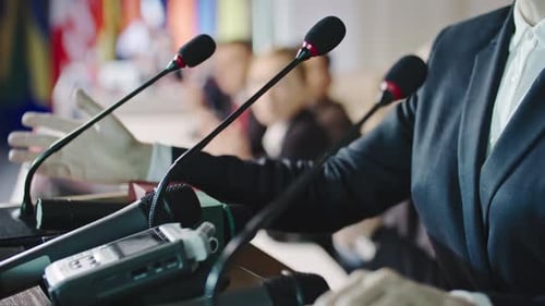 Microphones and a Speaker Giving a Press Conference