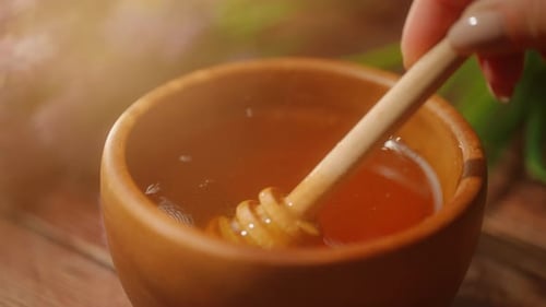 A Person is Dipping Wooden Spoon in Honey