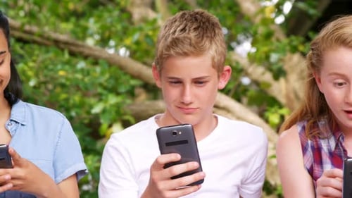 Teens Using Cellphones Together Outside