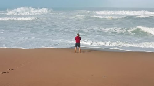 Adult Contemplating Waves on Sandy Beach