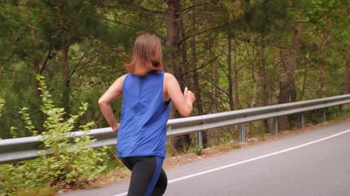 Woman Jogging on Road Through Green Nature
