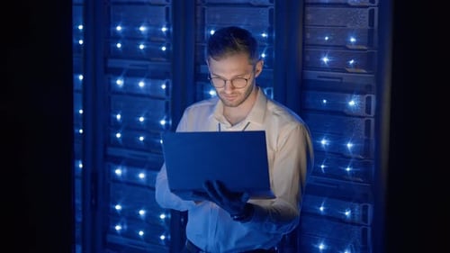 Young Adult Working on Laptop in Server Room
