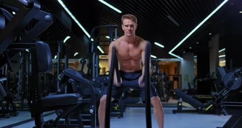 Professional Athlete Doing Exercises with Battle Ropes in a Modern Gym