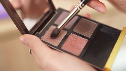 O maquiador usa pincel e cosméticos decorativos durante a fabricação de maquiagem