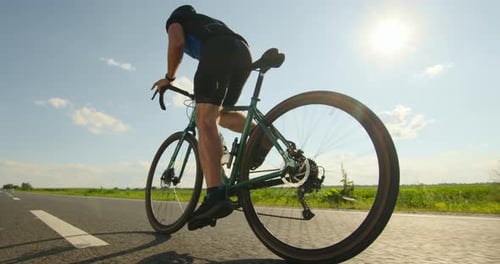 Ein Sportler auf einem Fahrrad steht auf den Pedalen und entwickelt eine hohe Geschwindigkeit