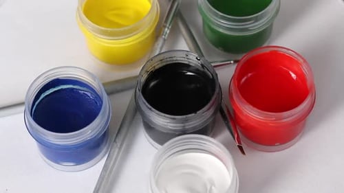 Un ensemble de gouache et de pinceaux. Ouvrez des pots de peinture. Faites pivoter la table des sujets. Gros plan.