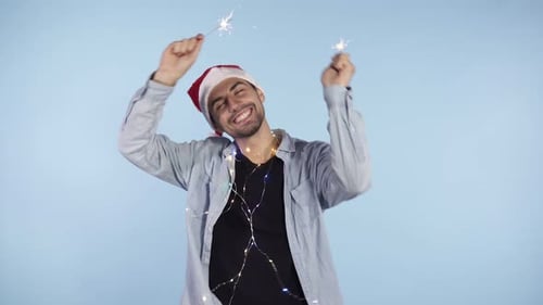 Man Celebrates Holding Sparklers and Wearing a Santa Hat