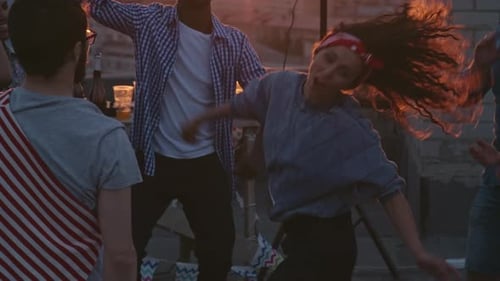 Friends Dancing on Rooftop Party at Sunset