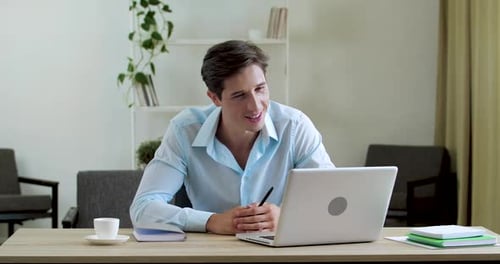 Hombre clásico sonriente se sienta a la mesa en casa en la oficina, usa la cámara web del portátil para comunicarse con