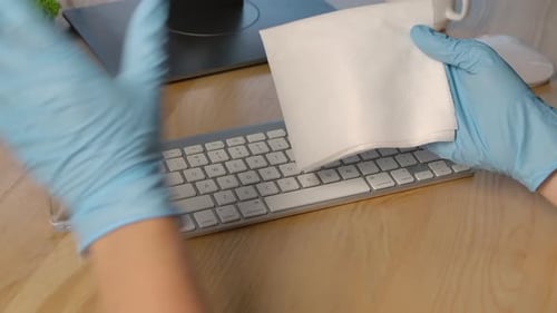 Sanitizing Keyboard with Wipe at Workplace